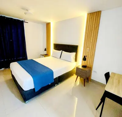 a bedroom with a bed with a blue blanket and a table at Mandala Lux Hotel in Pisco