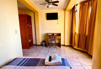 a bedroom with a bed and a table with a chair at Hospedaje Sol de Oro in Nazca
