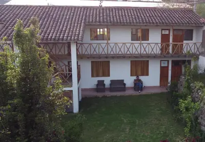 a white house with a porch and a yard at Hostal Miramonti in Urubamba