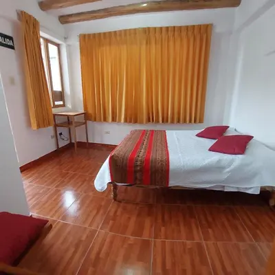 a bedroom with a bed with red pillows on it at Hostal Miramonti in Urubamba