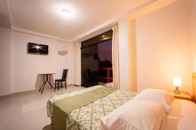 a bedroom with a bed and a table and a window at Hostal Los Balcones in Nazca