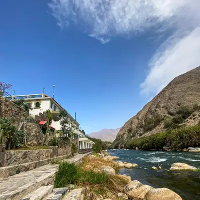 a river with a building next to a mountain at Villasol Hotel in Lunahuaná