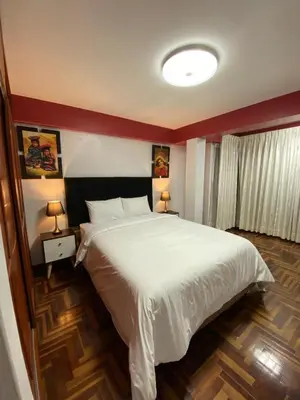 a bedroom with a large white bed and two lamps at Plaza del Inka in Cusco