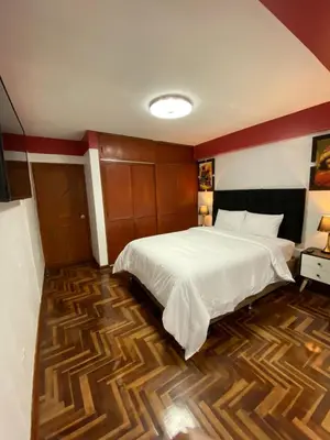 a bedroom with a white bed and a wooden floor at Plaza del Inka in Cusco