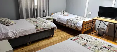 a room with two beds and a desk with a computer at Les Sorciers ooo in Cusco