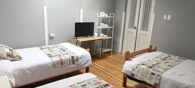 a room with two beds and a desk with a television at Les Sorciers ooo in Cusco