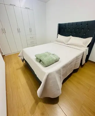a bed with a black headboard and two towels on it at El Oasis de Huacachina - Alojamiento in Ica