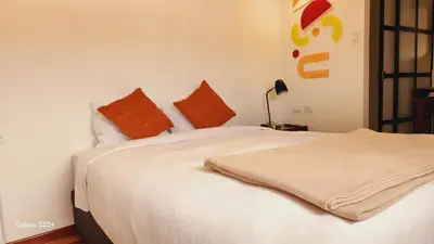 a bedroom with a white bed with orange pillows at Solara Art House Hotel in Cusco