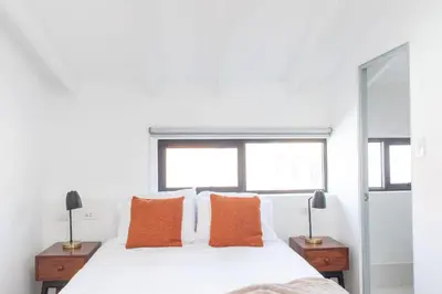 a bedroom with a white bed with orange pillows at Solara Art House Hotel in Cusco