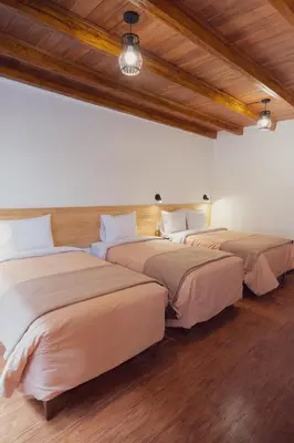 three beds in a room with wood floors and ceilings at Casa Alba Ollantaytambo in Ollantaytambo