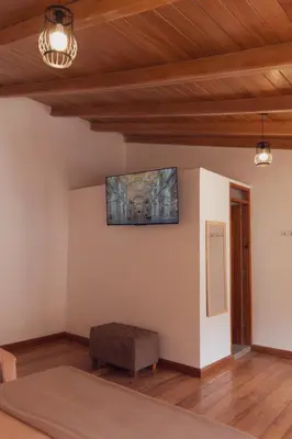 a room with a bed and a television on the wall at Casa Alba Ollantaytambo in Ollantaytambo