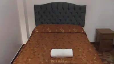 a bed with a black headboard and a white towel at IntiKilla in Mollepata