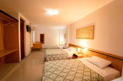 a hotel room with three beds and a television at Hostal Los Balcones II in Nazca
