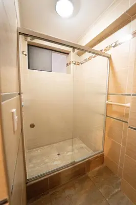a shower with a glass door in a bathroom at Hostal Los Balcones II in Nazca