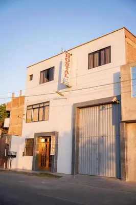 a white building on a street with a garage at Hostal Los Balcones II in Nazca