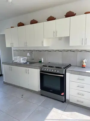 a kitchen with white cabinets and a black oven at Casa de Campo en Cieneguilla in Hacienda Cienguilla