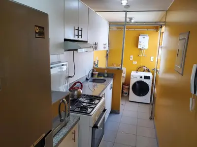 a small kitchen with a stove and a sink at Edificio Parque Suarez - San Miguel in Lima