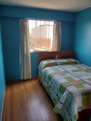 a blue bedroom with a bed and a window at Edificio Parque Suarez - San Miguel in Lima