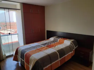 a bedroom with a bed and a large window at Edificio Parque Suarez - San Miguel in Lima
