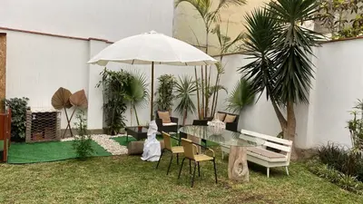 a patio with a glass table with chairs and an umbrella at Hermosa habitación independiente cerca a Miraflores in Lima