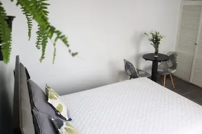 a white bed in a room with a table and chairs at Hermosa habitación independiente cerca a Miraflores in Lima