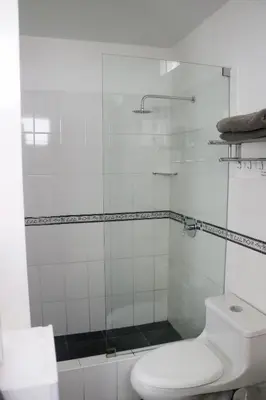 a bathroom with a toilet and a glass shower at Hermosa habitación independiente cerca a Miraflores in Lima
