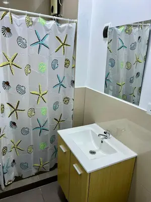 a bathroom with a sink and a shower curtain at Surfer Hostel El Quilla Punta Hermosa in Punta Hermosa