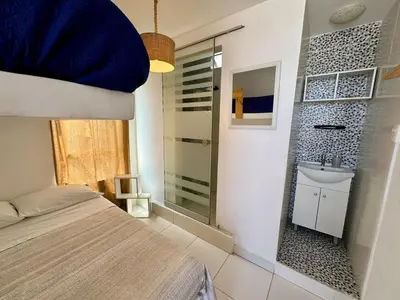 a bedroom with a bed and a bathroom with a sink at Surfer Hostel El Quilla Punta Hermosa in Punta Hermosa