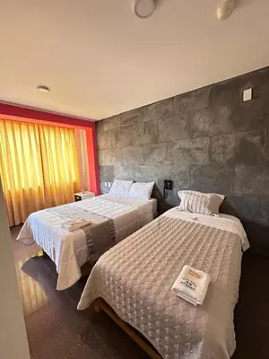 a bedroom with two beds and a stone wall at Hotel Atenas City in San Andrés