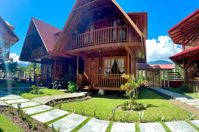 a wooden house with a balcony and a yard at DCampos Lodge in Oxapampa