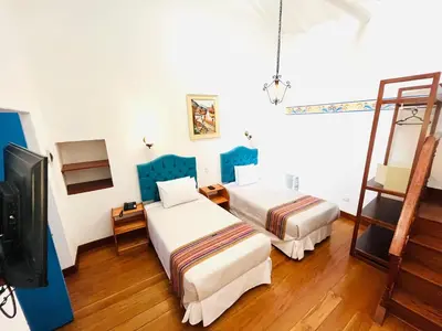 a hotel room with two beds and a television at Rojas Plaza Boutique in Cusco