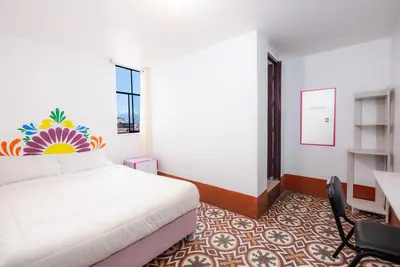 a bedroom with a white bed and a desk and a window at Retablo Boutique Hotel in Ayacucho