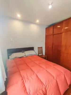 a bedroom with a large orange bed with a wooden cabinet at Cusco Central Complete Apartment in Cusco