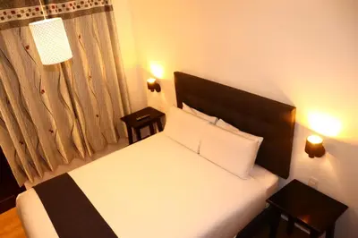 a bedroom with a bed with two tables and two lamps at Tikal Inn Machupicchu in Machu Picchu