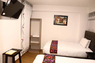 a small room with two beds and a flat screen tv at Tikal Inn Machupicchu in Machu Picchu