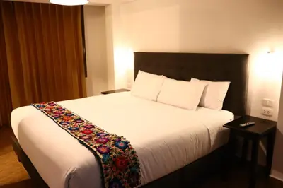 a bedroom with a large white bed with a flower blanket on it at Tikal Inn Machupicchu in Machu Picchu