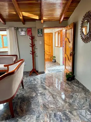 a living room with a stone floor and a wooden door at Rumiwasi Inn Apartament in Ollantaytambo