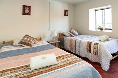 a room with two beds and a window at Munay Tika house in Cusco