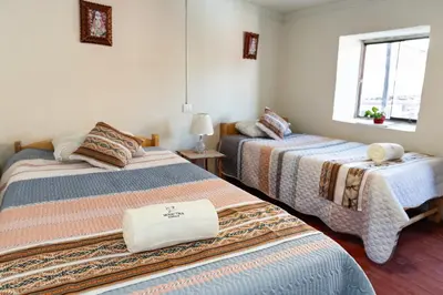 a room with two beds and a window at Munay Tika house in Cusco