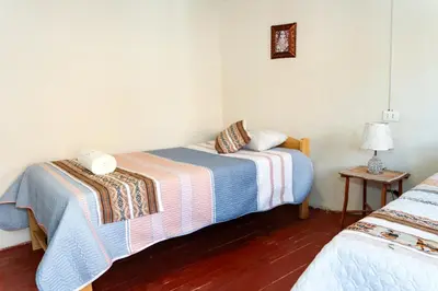a bedroom with two beds and a table with a lamp at Munay Tika house in Cusco