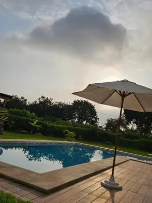 an umbrella sitting next to a swimming pool at Alquiler Casa de Campo Asia Cañete in San Andrés