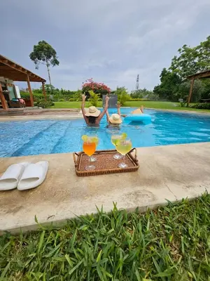 two people swimming in a swimming pool with drinks at Alquiler Casa de Campo Asia Cañete in San Andrés