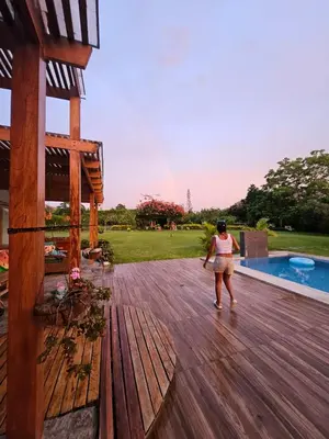 a woman standing on a wooden deck next to a pool at Alquiler Casa de Campo Asia Cañete in San Andrés