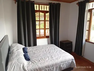 a bedroom with a bed with black curtains and a window at Casa Las Palmeras in Oxapampa