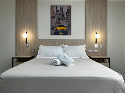 a bedroom with a large white bed with two lamps at Residencial Mar Caribe in Lima