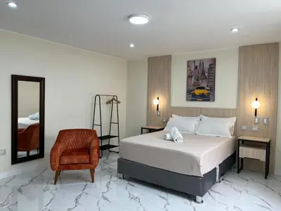 a bedroom with a bed and a chair and a mirror at Residencial Mar Caribe in Lima
