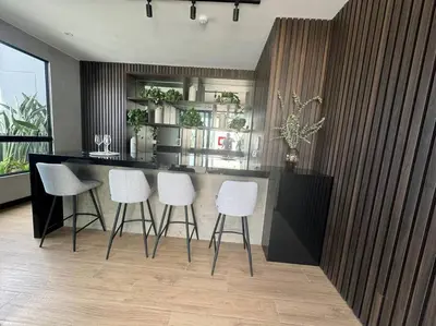 a kitchen with a bar with white stools at Departamento de Estreno Lima Miraflores in Lima