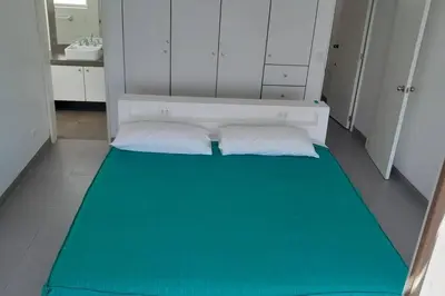 a small room with a bed with a green blanket at Gaviotas de Paracas in Paracas