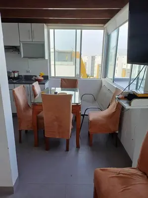 a living room with a table and chairs and a kitchen at Gaviotas de Paracas in Paracas