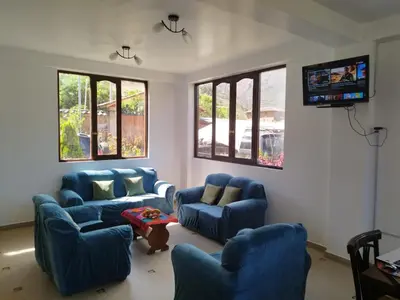 a living room with blue couches and a tv at Casa de Campo Apu San Isidro in Urubamba